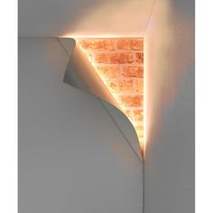 the corner of a room with a brick wall and light coming from it's side