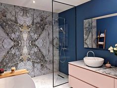 a bathroom with blue walls and marble counter tops, including a large white bowl sink