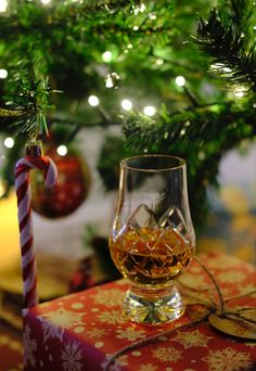 a glass of whiskey sitting on top of a table next to a christmas tree