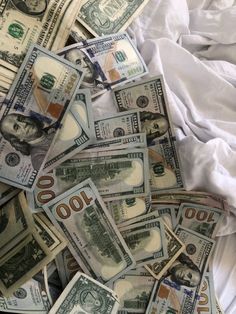 a pile of twenty dollar bills laying on top of a white sheeted bed spread