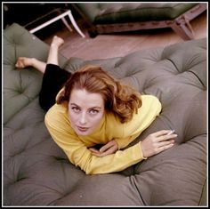 a woman laying on top of a brown futon couch next to a green chair