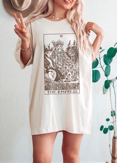 The Empress Tarot Card Shirt Please reach out if your desired color, size or garment style is not available! Be sure to check the size chart within the listing. Most of the models are wearing oversized apparel. Size up from your usual size to achieve this look! TEE INFO/CARE: * Solid colors are 100% cotton except Ash - 99% cotton and 1% polyester, heather colors are 52% cotton and 48% polyester * Pre-Shrunk * Unisex, Loose fit * Wash inside out in COLD water * Lay flat to dry or machine dry on LOWEST setting * Iron on low * Do NOT dry clean Printed with eco-friendly DTG (Direct to Garment Printing) technique. Inks are water based, bio-degradable and non-toxic. Artwork is digitally transferred directly onto the fabric, giving it a worn-in look. The printed material will be less stiff than t Tarot Tshirt, The Empress Tarot, Witchy Clothes, Tarot Shirt, Tarot Card Shirt, Empress Tarot Card, Empress Tarot, Indie Clothing, Vintage Tarot