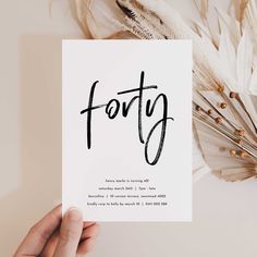 someone holding up a card with the word forty written in black ink on white paper