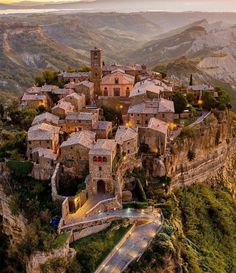 an aerial view of a village in the mountains at sunset with lights shining on it