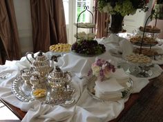 a table topped with lots of desserts and pastries on top of a white cloth covered table