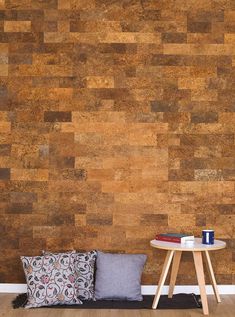 a table and some pillows in front of a wall with a wooden panel pattern on it