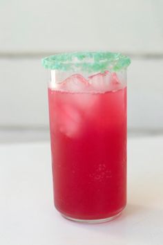 a red drink with green garnish in a glass on a white counter top