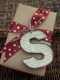 a gift wrapped in brown paper with polka dots and a red ribbon tied around the letter s