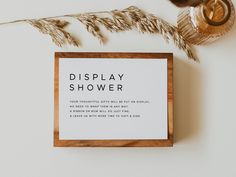 a display shower sign sitting on top of a table next to a candle and some dried plants