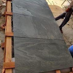 two men are working on a large slab of slate in the process of being installed