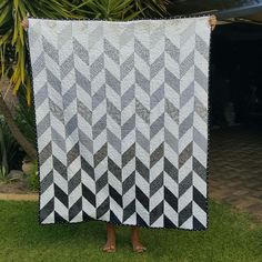 a woman holding up a black and white quilt