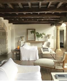 a living room filled with white furniture next to a fire place in a stone building