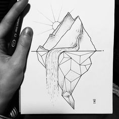 a hand holding up a piece of paper with a drawing on it that looks like an iceberg