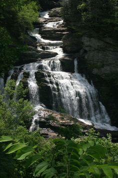 a waterfall in the woods with lots of water coming out of it's sides