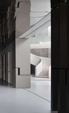 an empty hallway with white walls and black columns, leading to the upper level of a building