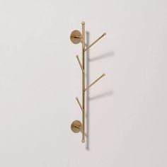 a wall mounted coat rack with three hooks and two balls on the top, in gold