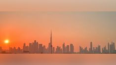 the sun is setting in front of a cityscape with tall buildings and skyscrapers