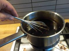 a person whisking something in a saucepan on top of a gas stove