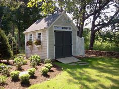 a small shed in the middle of some trees and grass with flowers growing on it