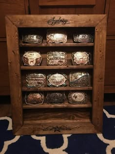 a wooden display case filled with lots of different types of wrestling belt buckles and rings