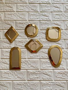 five mirrors are arranged on a white brick wall