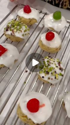 some cookies with white frosting and cherry toppings are on a wire cooling rack