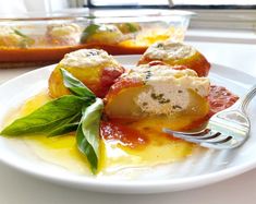 a white plate topped with ravioli covered in cheese and sauce next to a window