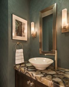 a bathroom sink sitting under a mirror next to a wall mounted faucet with lights on it