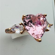 a pink heart shaped ring with two white diamonds