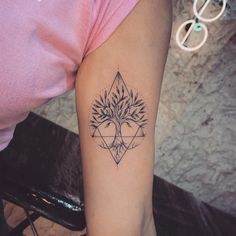 a woman's arm with a tree and triangle tattoo on the left side of her arm