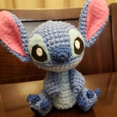 a crocheted stuffed animal sitting on top of a wooden table next to a chair