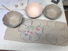 three bowls and two plates on a table with writing on the paper next to them