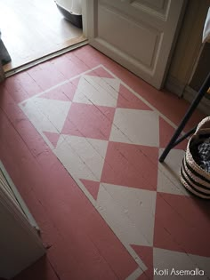 a pink and white checkered floor with a basket on the ground next to it