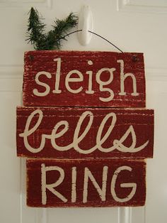 a sign that says sleigh bells ring hanging on the front door with pine branches