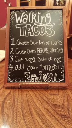 a chalkboard sign with writing on it sitting on top of a wooden table in a restaurant