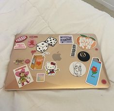 an open laptop computer sitting on top of a white bed covered in lots of stickers