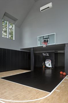 an indoor basketball court with several balls on the floor and a basket in the middle