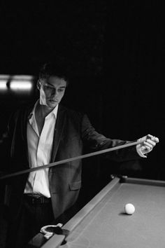 a man in a suit playing pool with a racket and ball on the table