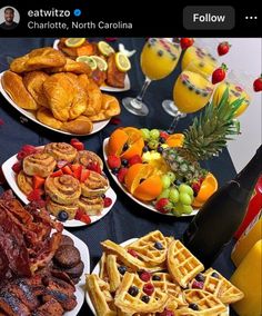 a table topped with plates of food next to glasses of orange juice and fruit on top of it