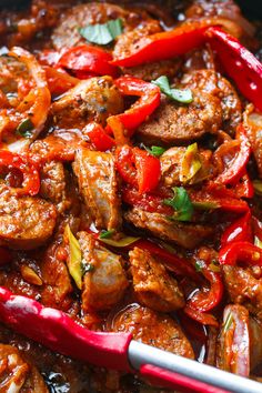 a close up of food in a pan with red spoons on the side,