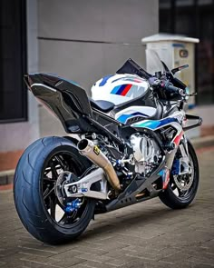 a white and blue motorcycle parked on the side of a road next to a building