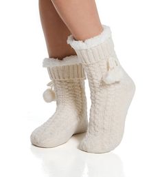 Slipper sock has fluffy sherpa (faux shearling) lining for a very cozy style. Soft cable knit has shimmery metallic threads. Pom-pom bow is sewn beneath cuff. Made of acrylic, polyester, metallic fibers. Sock has sherpa lining for extra softness and warmth. Ribbed knit cuff keeps sock in place. Decorative bow is sewn underneath cuff and has pom-pom detail. Metallic gold threads are woven into cable knit for shimmery look. Reinforced toe seam. Sole has anti-slip dots. Super cozy for cool weather. Cozy Winter Socks With Soft Texture, Warm Cozy Socks For Indoor Use, Cozy Warm Socks For Indoor Use, Cozy Warm Socks For Indoor, Cozy Soft Beige Socks, Cozy Round Toe Winter Socks, Super Soft Comfortable Cream Socks, Comfortable Super Soft Cream Socks, Comfortable Warm Cream Socks