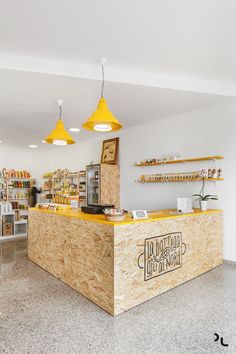 the inside of a store with yellow lights and shelving on the wall behind the counter