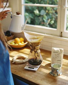 a woman pours coffee into a glass pitcher