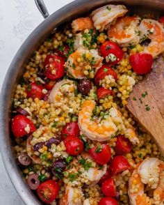 a pot filled with shrimp, tomatoes and couscous