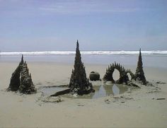 sand castle made to look like trees on the beach with ocean in background and blue sky