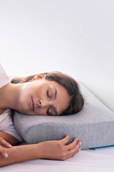 a woman laying on top of a pillow with her eyes closed and head resting on the pillow