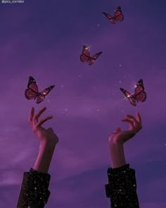 two hands reaching for butterflies flying in the air at night with purple and blue sky