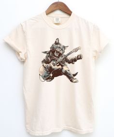 Elevate your style with this Rock Cat Guitar T-Shirt, a must-have for cat enthusiasts, music lovers, and festival-goers! This unique design showcases a charismatic cat rocking out on a guitar, blending humor, creativity, and cool vibes into one unforgettable graphic tee. Features: Bold Design: A professionally illustrated cat shredding a guitar in a rocker outfit, perfect for fans of rock and roll or quirky apparel. Versatile Style: Pair it with jeans, shorts, or even layer it under a jacket for Cat Playing Guitar, Rock Cat, Rocker Outfit, Retro Funny, Rock Outfit, Cat Lover Shirt, Cat Graphic Tee, Festival Shirts, Rock Concert