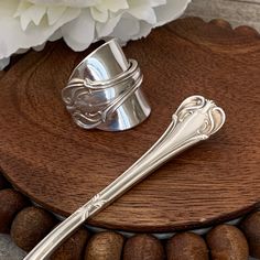 a silver spoon sitting on top of a wooden table next to some nuts and a white flower